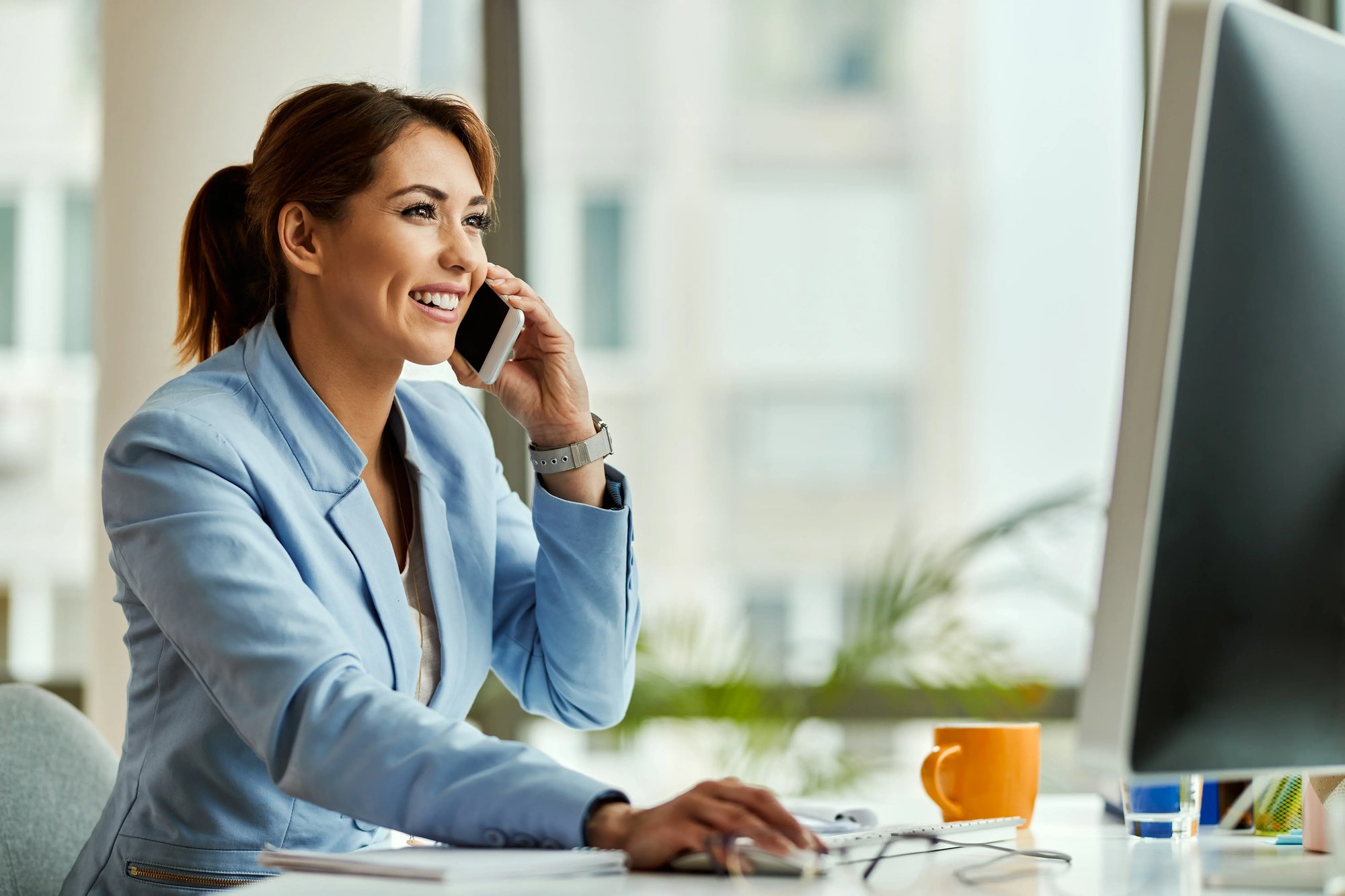 jeune-femme-affaires-heureuse-travaillant-ordinateur-bureau-communiquant-par-telephone-portable-au-b (1)